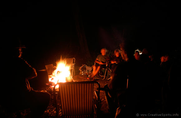 A group of Aboriginal people sits around a campfire.