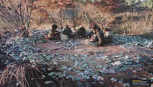 Aboriginal people drinking in the bush surrounded by dozens of empty cans.