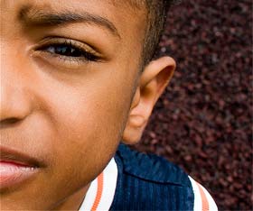 Aboriginal boy looking at camera with half his face visible.