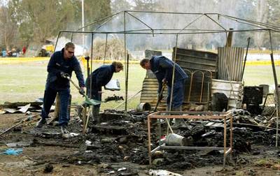Police officers rummaging in the smouldering remains of the tent embassy.