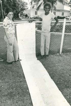 Two people standing outside with the Larrakia petition rolled out in front of them.