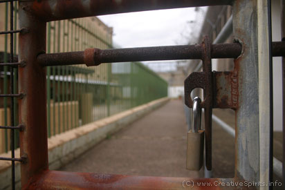 Circle sentencing: A lock bars the way into an outside corridor with fences to either side.