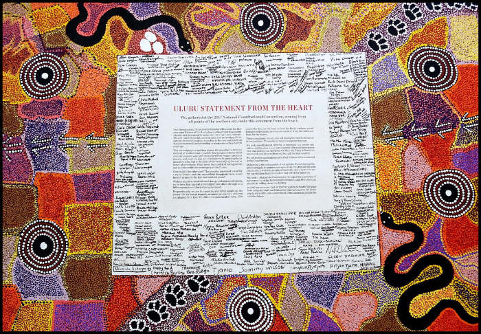 The canvas of the Uluru Statement from the Heart shows artwork around the text in the middle, and signatures of the delegates.