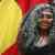 A proud Indigenous girl in front of the Aboriginal flag.