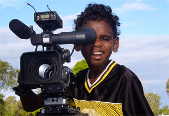 A young Indigenous boy behind a professional camera.