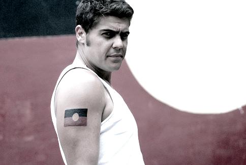 Dan Sultan portrait in front of an Aboriginal flag.